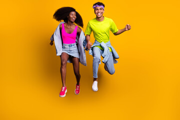 Canvas Print - Full length body size view of handsome beautiful trendy cheery couple jumping holding hands isolated on bright yellow color background