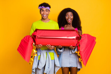 Sticker - Portrait of attractive funky cheerful couple holding in hands large fake candy having fun isolated on bright yellow color background