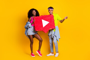 Poster - Photo of excited sweet young people wear jeans clothes holding big video recorder sign isolated yellow color background