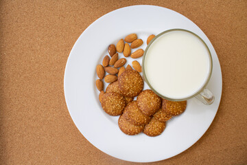 round cookies, nuts on a white plate. glass of milk