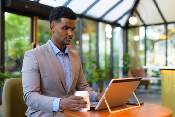 Wall Mural - African businessman at coffee shop working using laptop computer