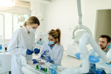 The female dentist and the assistant prepare the instruments for the dental examination.