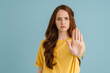 © Drobot Dean - Young ginger white woman showing stop gesture and looking at camera