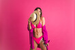 © Анастасия Каргаполов - Beautiful fit tanned sporty woman in bikini straw hat and shirt on pink background