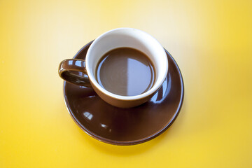 Poster - High angle shot of a cup of hot coffee isolatedon a yellow surface