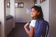 © WavebreakMediaMicro - Portrait of smiling african american schoolgirl standing in school corridor wearing schoolbag
