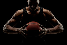 Basketball Player Holding A Ball Against Black Background. Serious Concentrated African American Man