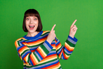 Sticker - Photo of shocked happy young woman point fingers empty space sale news offer isolated on green color background