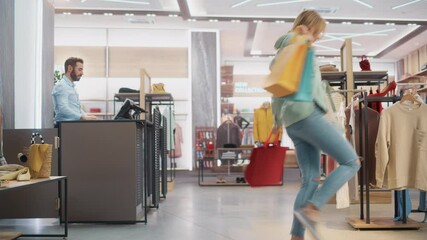 Wall Mural - Clothing Store: Young Woman at Counter Takes Shopping Bags with Clothes from Friendly Retail Sales Assistant, Goes Away in Happy Mood, Smiling, Spinning and Dancing. Fashion Shop with Designer Brands.