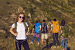 © Studio Romantic - Young girl tourist in glasses with a backpack on a hiking trip in the mountains on a hill in summer nature. Leisure. People with backpacks travel along the route in the mountains.