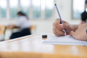 Wall Mural - Girl Student in exam test school, Side View of high school or university holding writing document paper answer sheet and lecture final exams in classroom with white uniform pupil of Thailand