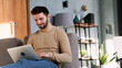 © AboutLife - Portrait of smiling man with laptop sitting on the couch