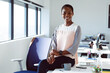 © Wavebreak Media - Smiling african american businesswoman sitting on desk at work