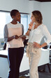© Wavebreak Media - Two diverse businesswomen standing, using tablet and talking at work