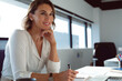 © Wavebreak Media - Smiling caucasian businesswoman sitting at desk, making notes at work