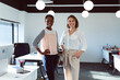 © Wavebreak Media - Two smiling diverse businesswomen standing and looking at camera at work
