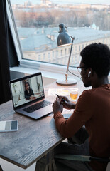 Wall Mural - Rear view of businessman talking to his colleague on laptop during online meeting