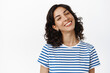 © Cookie Studio - Portrait of happy pretty girl with dark curly hair, pierced nose, smiling white teeth, looking positive and upbeat, enjoying life, standing in summer t-shirt against white background