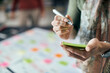 © Drazen - Close-up of female entrepreneur writing on adhesive note while working in the office.