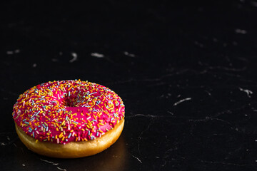 Closeup shot of a glazed donut with sprinkles isolated on a black background