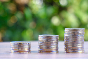 Sticker - Saving money concept, stacking coins on green bokeh background, advertising coins of finance and banking