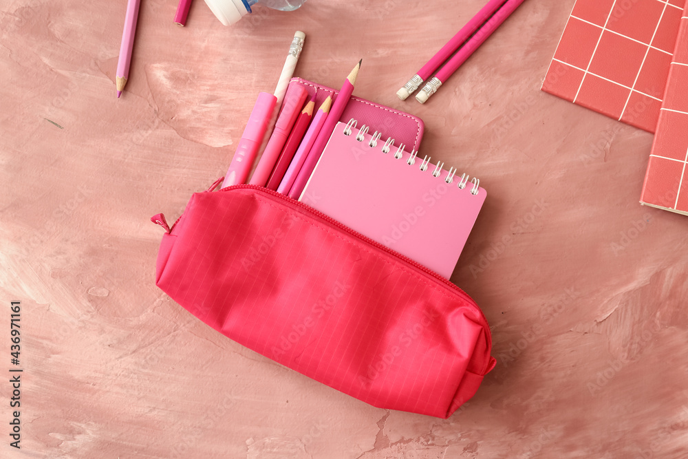 Pencil case with stationery on color background