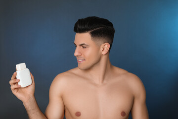 Wall Mural - Handsome man holding post shave lotion on blue background