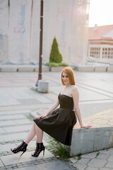 Wall Mural - Caucasian female with a black dress sitting in a park