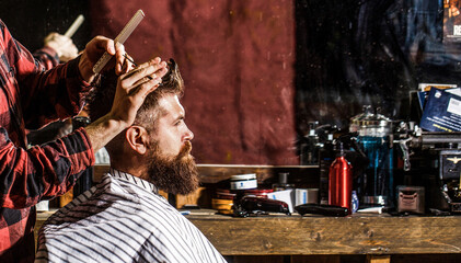 Hairstylist serving client at barber shop. Man visiting hairstylist in barbershop. Bearded man in barbershop. Work in the barber shop. Hairdresser cutting hair of male client