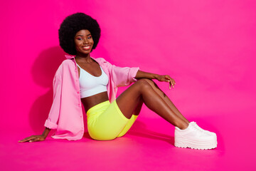 Poster - Photo of sweet adorable dark skin woman dressed crop top smiling sitting floor isolated pink color background