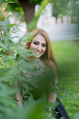 Sticker - Young attractive woman in a black dress smiling and posing in the green park