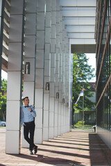 Wall Mural - Young handsome elegant man in a blue suit and bow posing outdoors