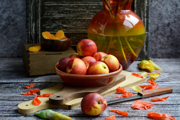 Wall Mural - Still life of juicy peaches in a bowl and yellow iris flowers in a vase on a dark wooden background