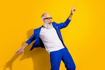 Wall Mural - Photo of crazy happy cheerful old man look empty space wind fly blazer wear glasses isolated on yellow color background
