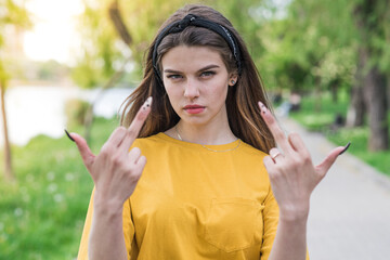 Portrait of a young and beautiful caucasian girl showing middle fingers