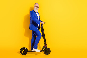 Sticker - Full size photo of happy smiling good mood mature businessman riding eco scooter isolated on yellow color background