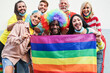 Gay people smiling at pride parade with LGBT flags while wearing protective face mask - Main focus on left girl face