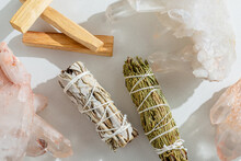 White Sage, Cedar, Crystals, And Palo Santo Sticks Tied By A Bundle On A Light Background. A Set Of Incense For Fumigation. Top View. Organic Incense From Latin America. Color Photo Close-up.