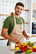 Cheerful young man preparing healthy food in the kitchen