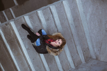 Caucasian female with a coat sitting on stone stairs