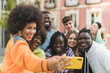 © ADDICTIVE STOCK - Happy multiethnic friends taking selfie on smartphone in town