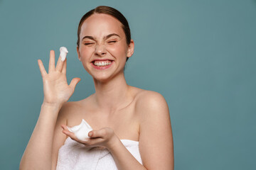 Wall Mural - Ginger woman wearing towel smiling while showing cosmetic foam