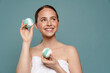 © Drobot Dean - Ginger woman wearing towel smiling while showing balls bath bomb