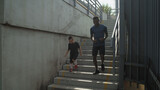 Fototapeta Na drzwi - Diverse father and son running on concrete staircase together