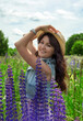 Beautiful woman with lupin flowers in summer field