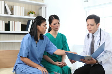 Team of doctors and businesswoman having a meeting in medical office,Multiracial team of doctors discussing a patient standing grouped in the foyer looking at a tablet computer