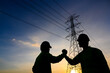© เลิศลักษณ์ ทิพชัย - The silhouette of an electrical engineer with a worker Talk to each other and shake hands to agree on the production of electric power. Planned by producing power at the high voltage electrodes.