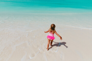 happy little girl play with water on beach, family vacation