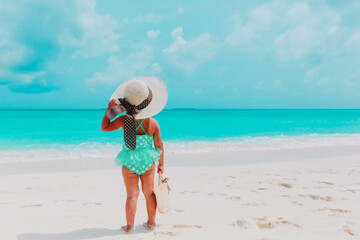 rear view of little girl in big hat on summer beach