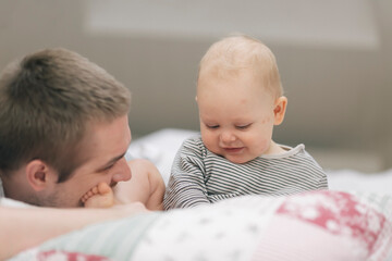 child playing with father on bed in attic room, father's day